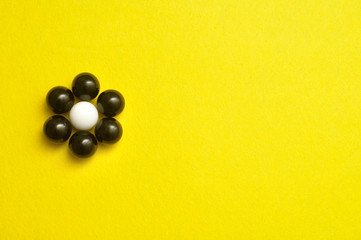 White and black balls packed in the shape of a flower isolated on a yellow background