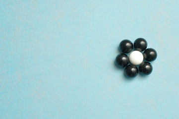 White and black balls packed in the shape of a flower isolated on a blue background