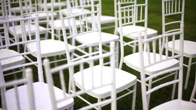 White wedding chairs chiavari on a green lawn, without decoration-