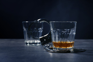 Glasses with handcuffs on dark background. Alcohol dependence concept