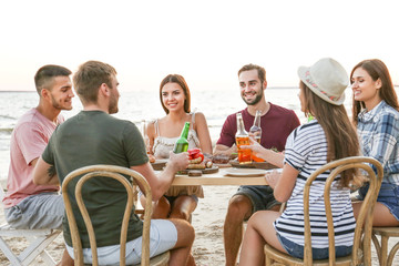 Young people having barbecue party on beach