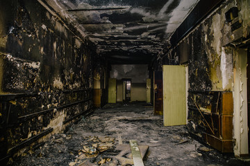Fototapeta na wymiar Dark dirty corridor in soot and ash, burnt-out abandoned building, fire consequences concept