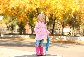 Cute little girl with umbrella in autumn park