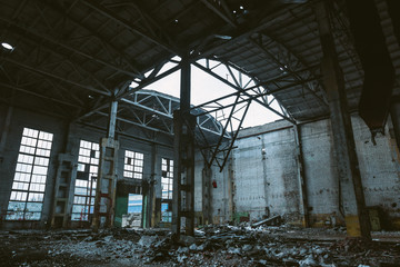 Ruins of large hall of abandoned warehouse or factory, consequences of catastrophe, war, hurricane, earthquake or other natural disaster