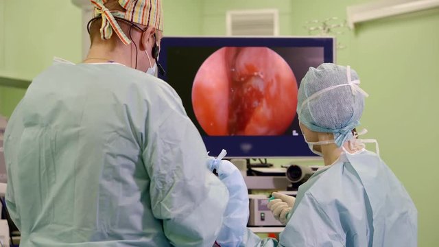 surgeon and his assistant are performing operating endoscopic method, doctor is inputting endoscope into a humans body
