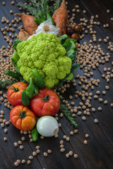 Fresh vegetables and chickpeas on wooden board. Vertical. Vegan and healthy food.