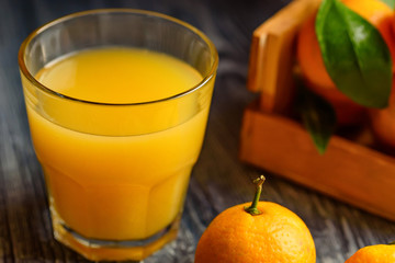 Glass of fresh juice and mandarins on table