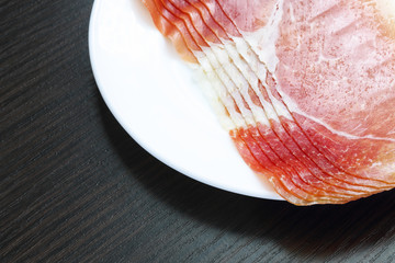 Sliced jamon (hamon) or prosciutto on a wooden background