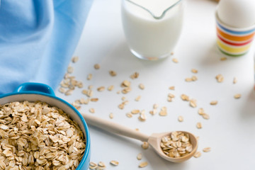 Oat flakes plate with milk, orange, eggs on a wooden white table. Top view of healthy oat flakes breakfast. Copy space. blue napkin Breakfast in bed plate, breakfast table buffet. Healthy ingredients