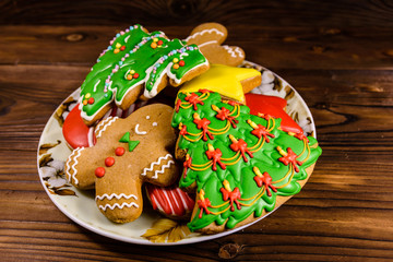 Plate with different christmas gingerbread cookies on wooden table