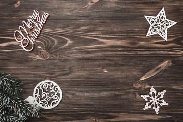 View from above of a Merry Christmas inscription and handmade tree toys on wooden background,...