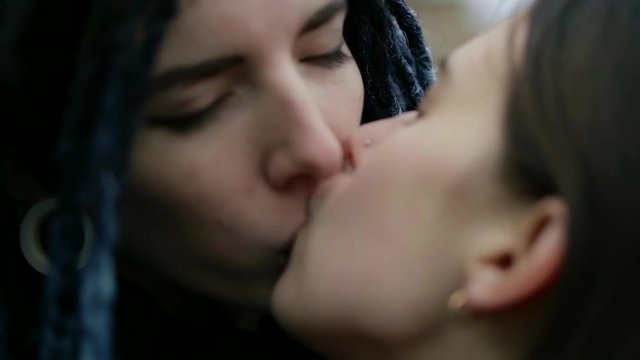 lesbian couple is kissing passionately outdoors in daytime, close-up shot of women faces