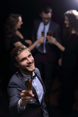 stylish young man standing with a glass of champagne.