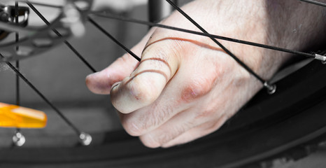 The panorama of Man pumping bicycle tyre outdoors, close-up of hands