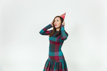 Beautiful caucasian fun young happy woman in plaid dress and birthday party hat with shy charming smile and brown hair, celebrating and enjoying holiday on white background isolated for advertisement.