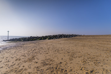 Fototapeta na wymiar Rock formation on sandy beach against blue coastal skyline