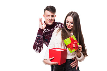 Couple celebrating a special date with a gift. Man show okay gesture while excited woman open geft on white background