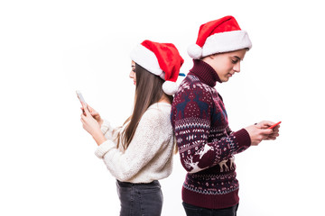 . Couple lovers are browsing, typing, reading at their pda, standing back to back, wearing santa hat on white background