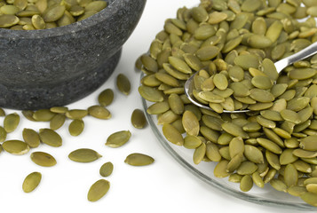 Green pumpkin seeds and black ceramic bowl