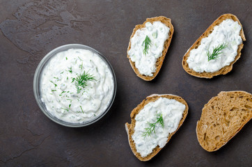 Homemade greek tzatziki sauce in a glass bowl with sliced bread
