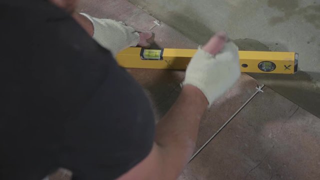 Professional worker laying tiles on floor