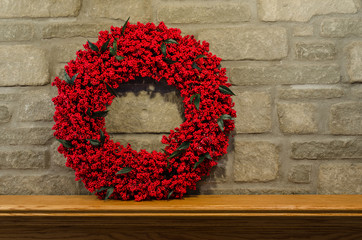 Red Berry Wreath on the left side of a  fireplace's mantel