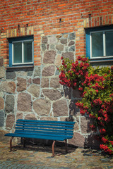 Steinwand mit Rosen Ranke und blauer Bank