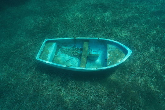 A small sunken boat underwater on the seafloor with seagrass leaves, Mediterranean sea, Catalonia, Costa Brava, Spain