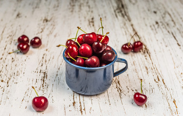 Cup with fresh colorful organic black cherries fruit against wooden background. Healthy food, vegan and vegetarian concept.