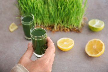 Woman holding shot of wheat grass juice, close up
