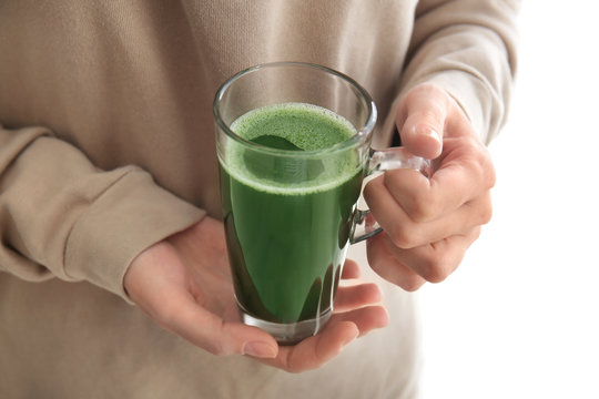 Woman holding glass cup of wheat grass juice, close up