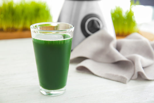 Glass of wheat grass juice on table