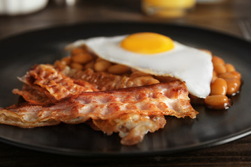 Plate with fried egg, bacon and beans, closeup