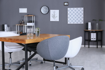 Modern office interior with wooden table and armchairs