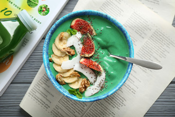 Bowl of green spirulina smoothie with fruits on table. Healthy vegan food concept