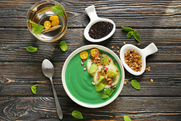 Bowl with green spirulina smoothie on table. Healthy vegan food concept