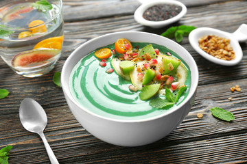 Bowl with green spirulina smoothie on table. Healthy vegan food concept