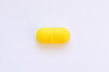 one yellow pill on white isolated background