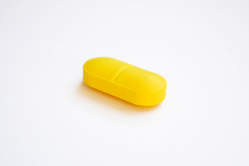 one yellow pill on white background