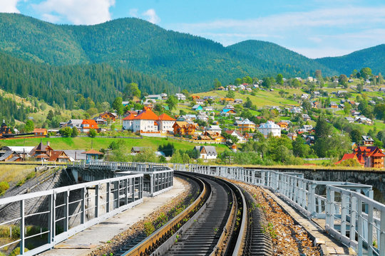 Fototapeta Railway through village in mountains