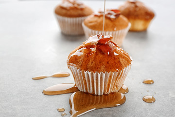 Pouring maple syrup onto tasty bacon muffin on table