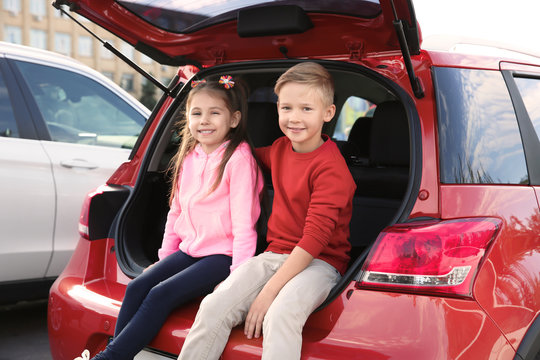 Cute children sitting in car trunk