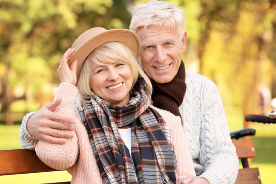 Cute elderly couple sitting on bench in autumn park