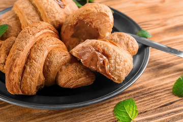 Plate with tasty croissants on table, closeup