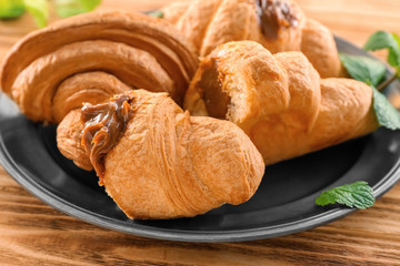 Plate with tasty croissants on table, closeup