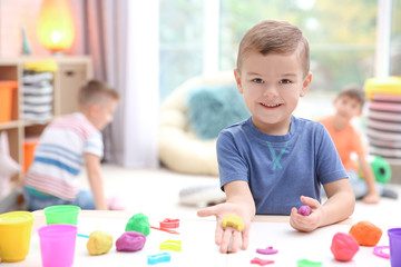 Little boy engaged in playdough modeling at daycare - obrazy, fototapety, plakaty