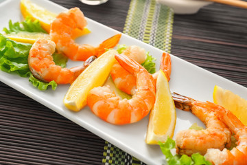 Delicious shrimps with lettuce and lemon on plate