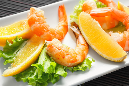 Delicious shrimps with lettuce and lemon on plate