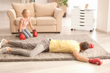 Cute girl and her father in boxing gloves playing at home