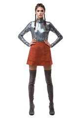 Young beautiful lady standing in light brown skirt and silver top with sequins and knee high boots on white background